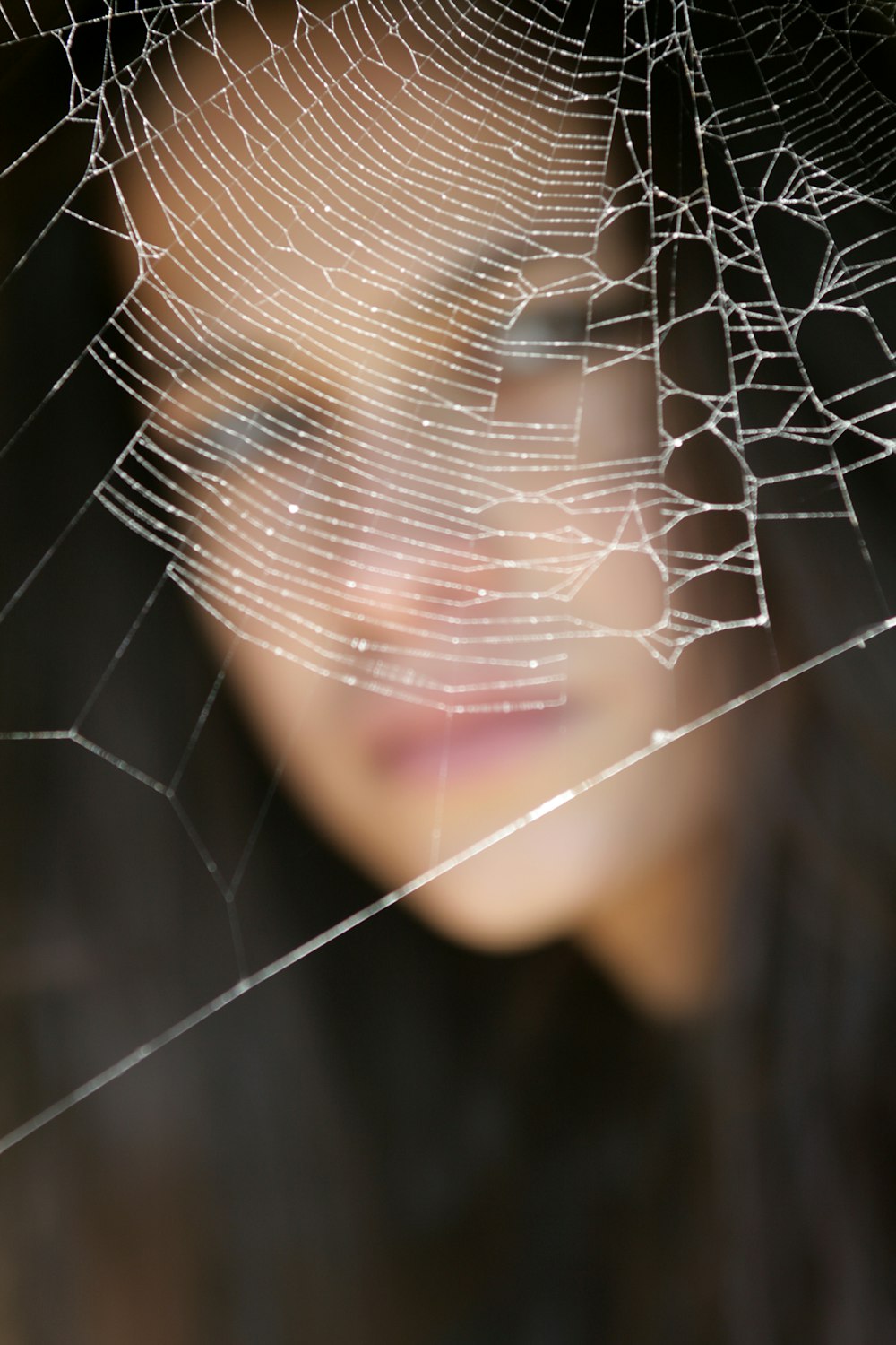 Frau im schwarzen Hemd mit Spinnennetz im Gesicht