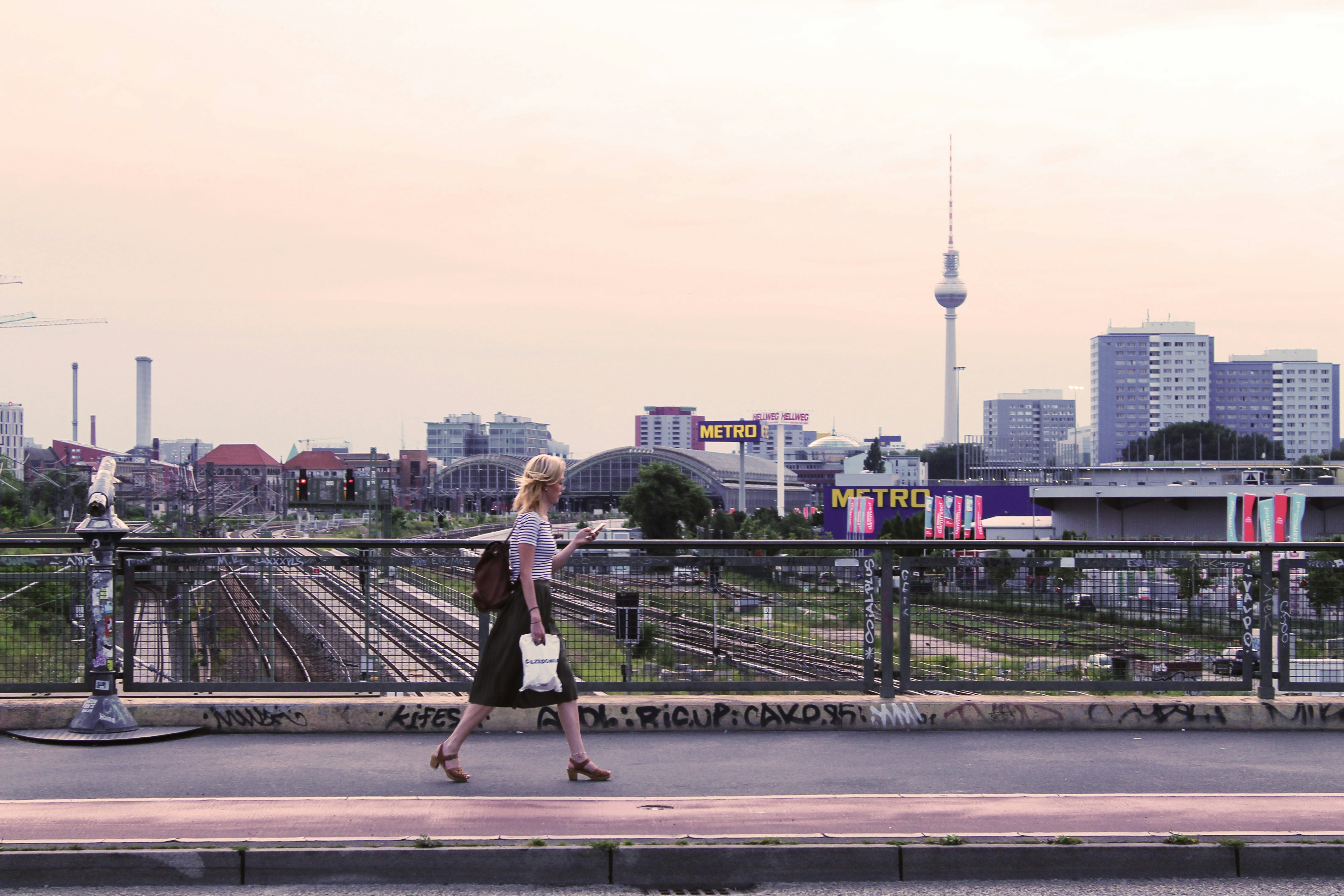 man in black t-shirt and black shorts walking on bridge during daytime