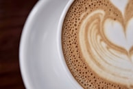 Close-up of a steaming cup of cappuccino with a heart-shaped foam design.