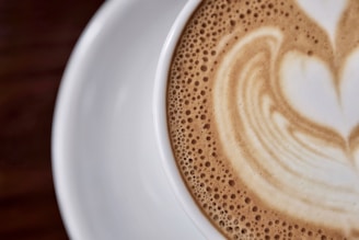 Close-up of a steaming cup of cappuccino with a heart-shaped foam design.