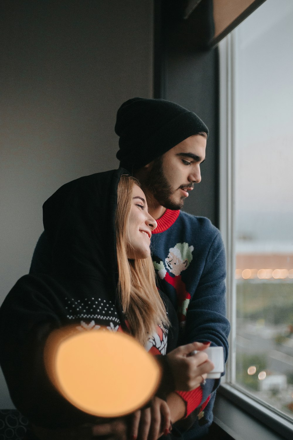 Hombre con sudadera con capucha negra y mujer con suéter rojo