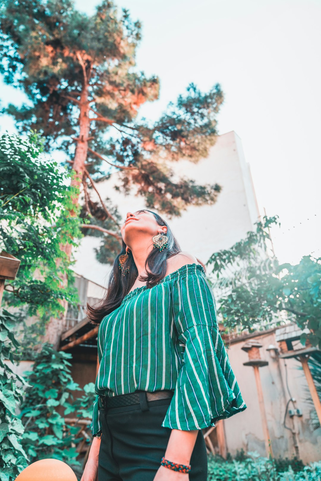 woman in green and red striped long sleeve shirt standing near tree during daytime