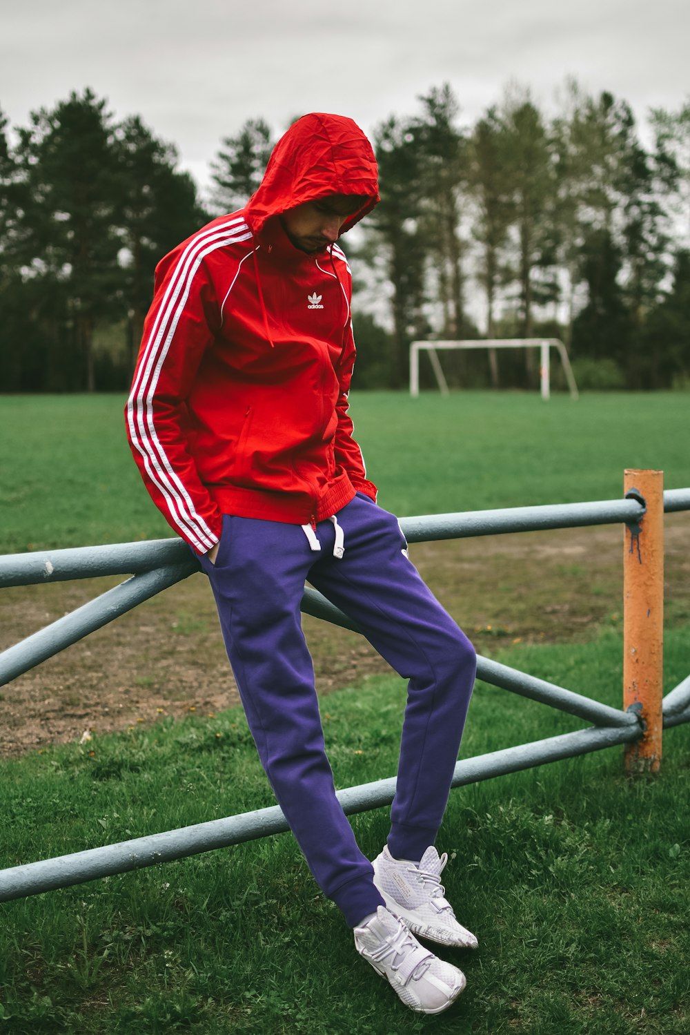 boy in red hoodie and blue pants standing on blue metal bar during daytime