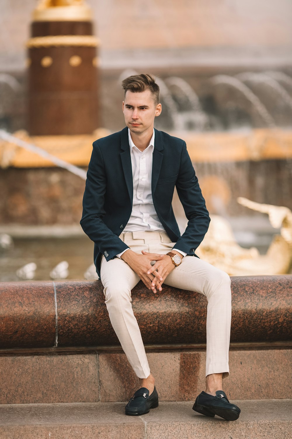 man in black suit sitting on brown concrete bench