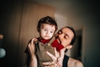 woman in black tank top carrying child in brown button up shirt