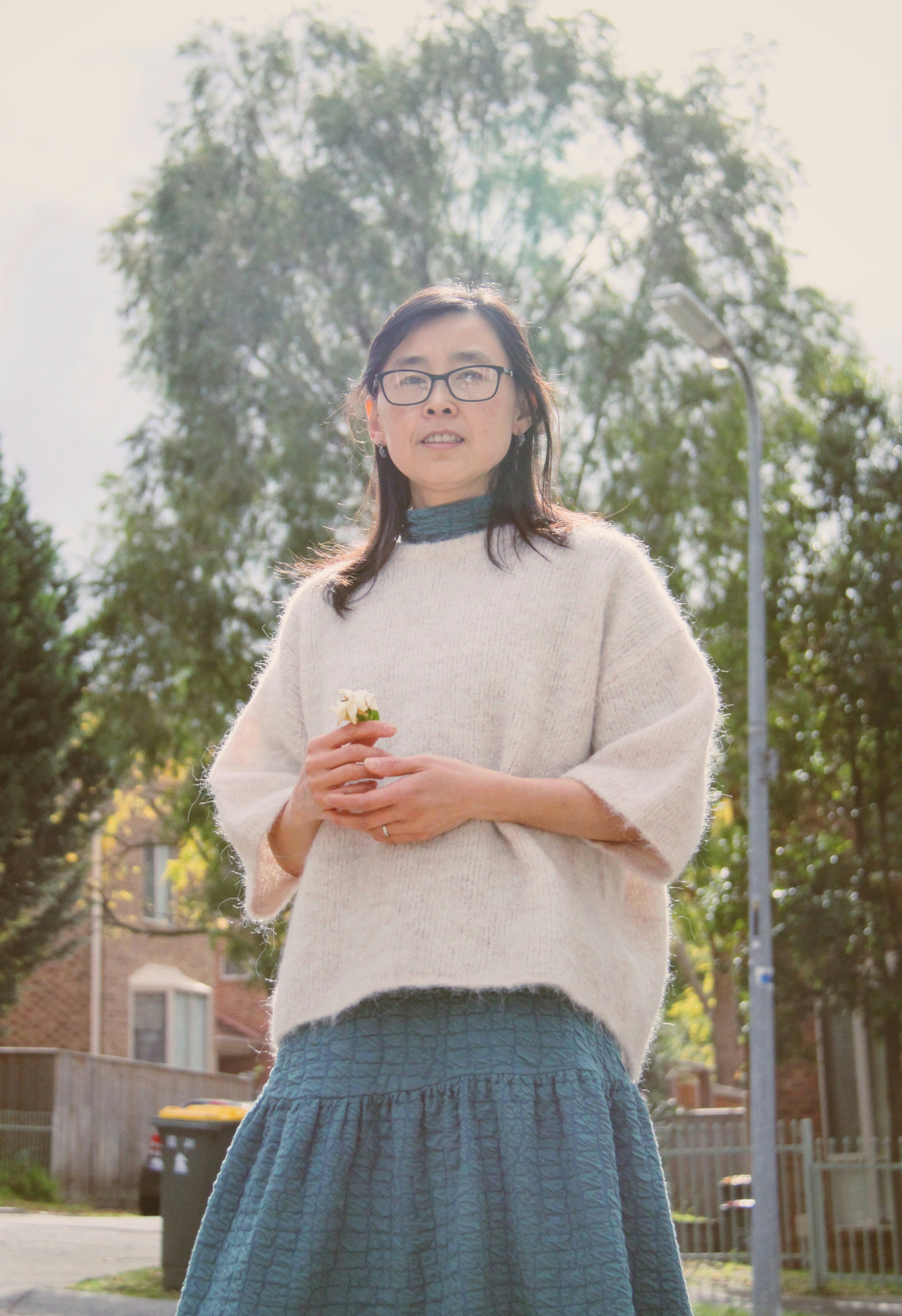 a woman in a white sweater and a blue skirt