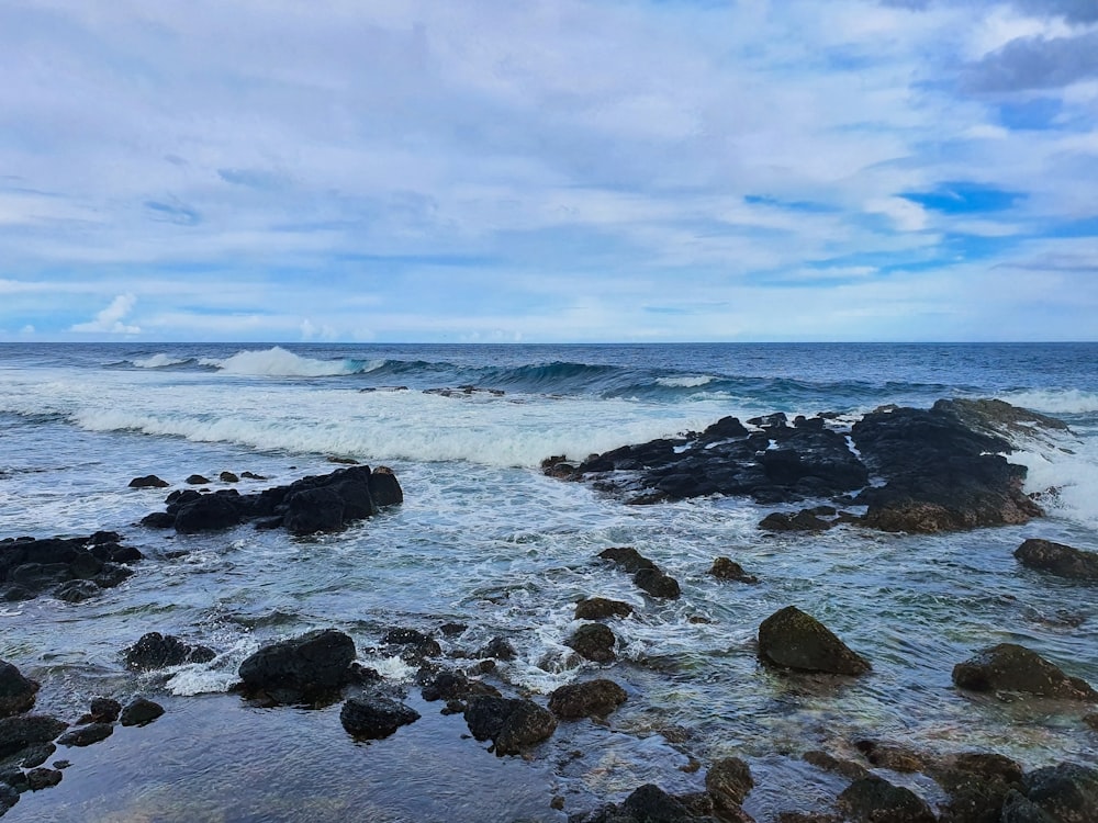 black rocks on sea shore under blue sky during daytime