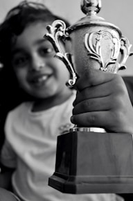 A smiling child receiving a scholarship certificate in a bright classroom setting.