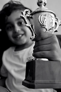 A proud young chess player holding a trophy after a spirited tournament win.