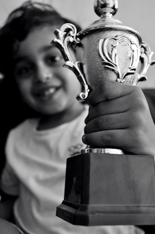 A smiling child receiving a scholarship certificate in a bright classroom setting.