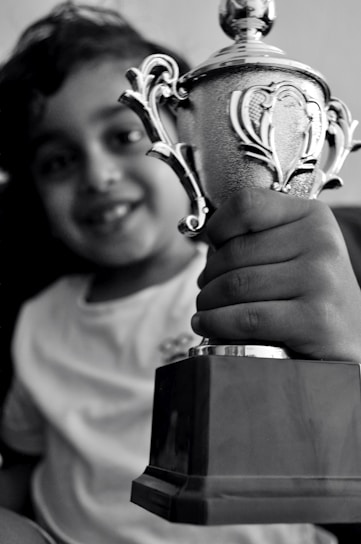 A smiling child holding a handmade 'esophageal atresia warrior' sign at a family support event.