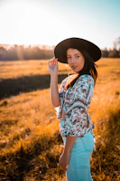A model wearing a bright, comfortable western outfit standing in a sunlit field with soft shadows.