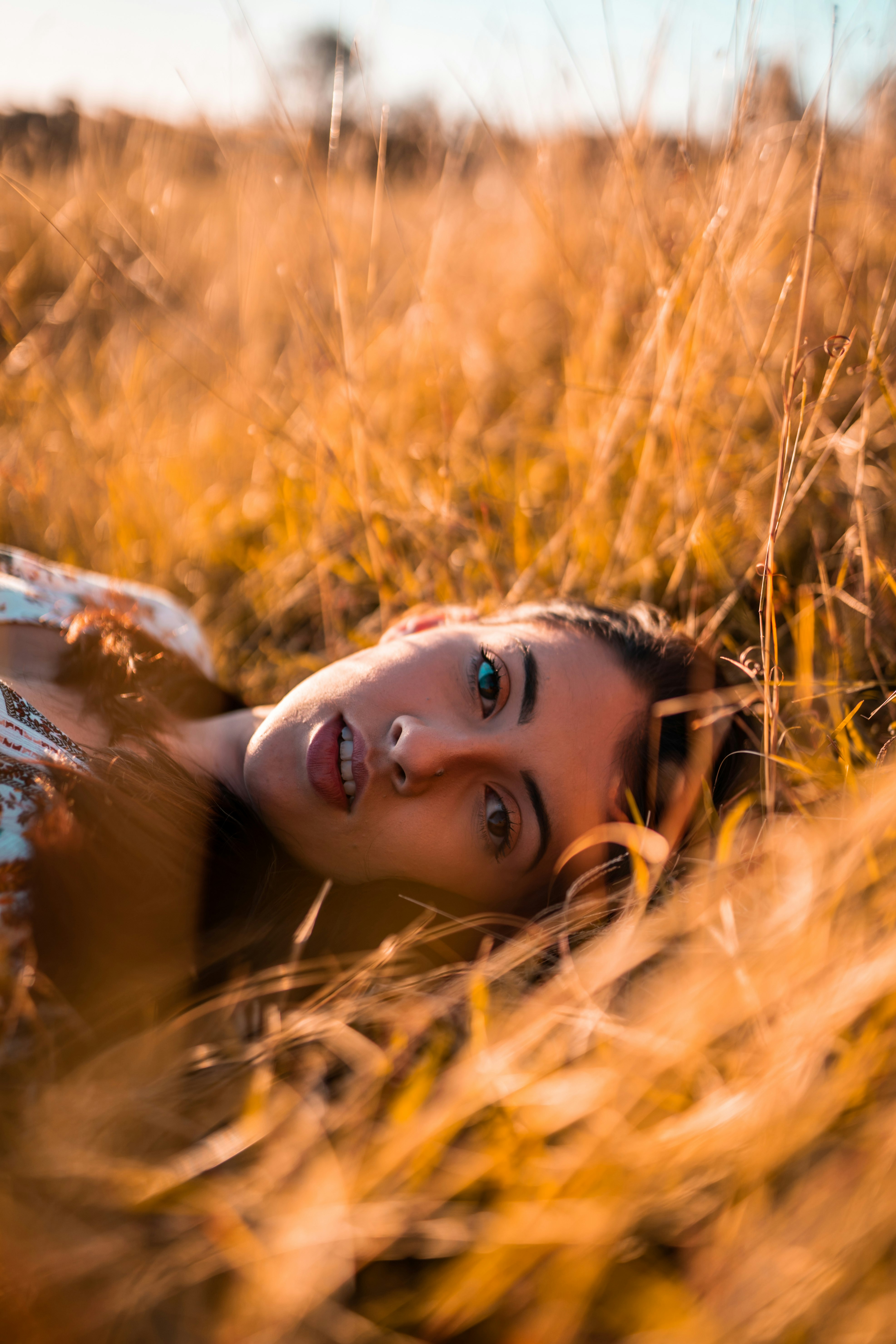 woman lying on brown grass field during daytime