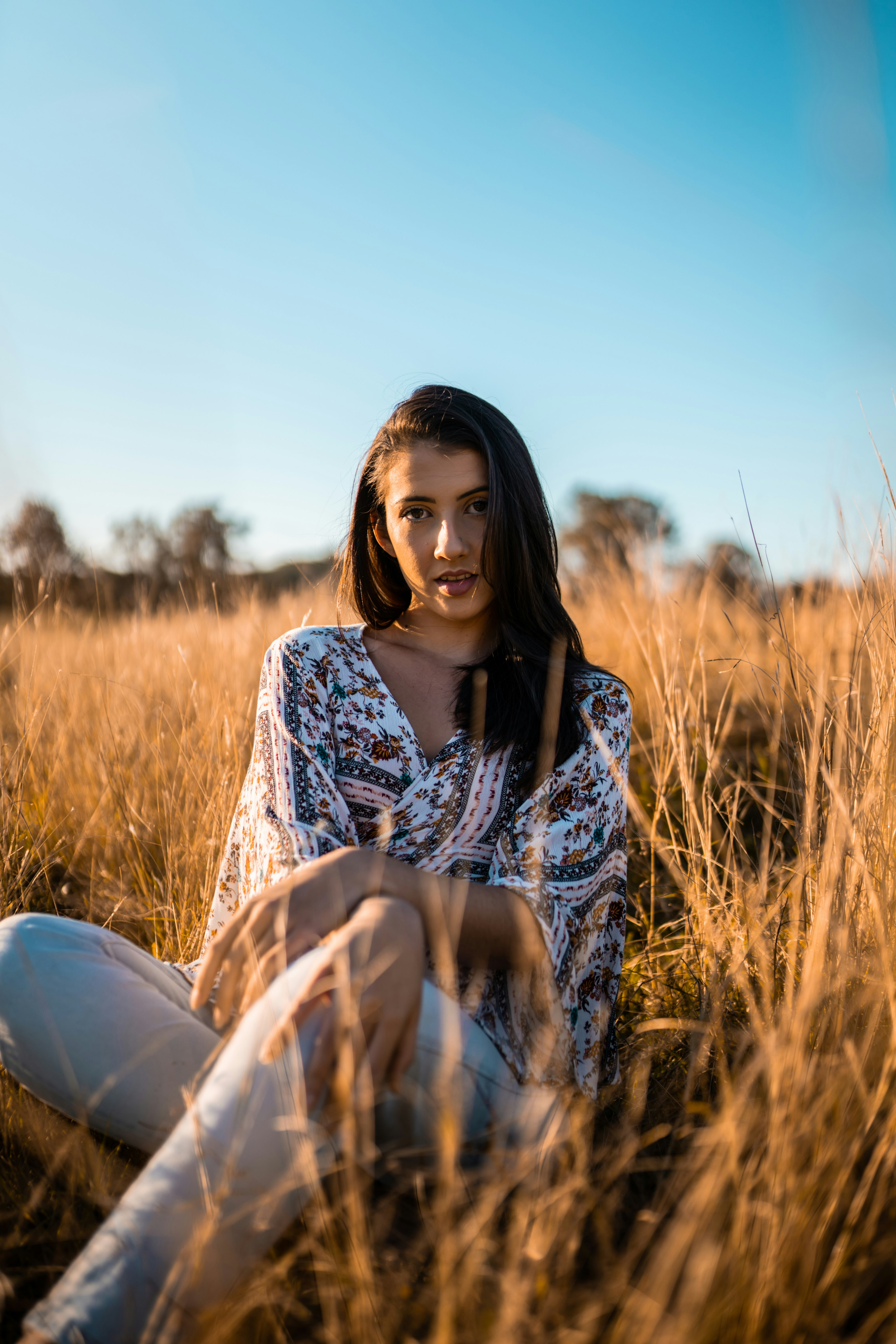woman in black and white long sleeve shirt sitting on brown grass field during daytime