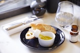 Close-up of hands pouring olive oil onto fresh bread at a family table