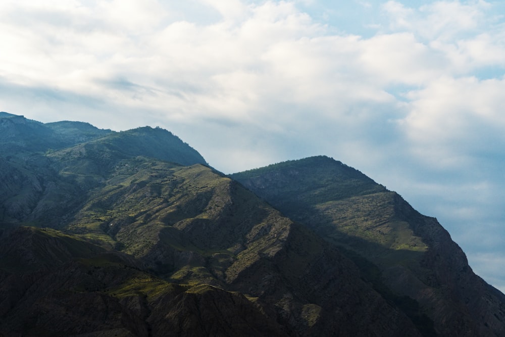 green and black mountain under white clouds during daytime