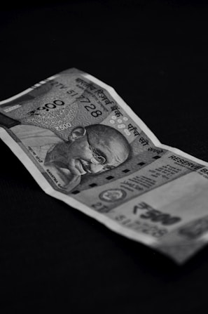 A black and white photograph of a 500 denomination Indian currency note displaying intricate designs and the portrait of a notable figure.