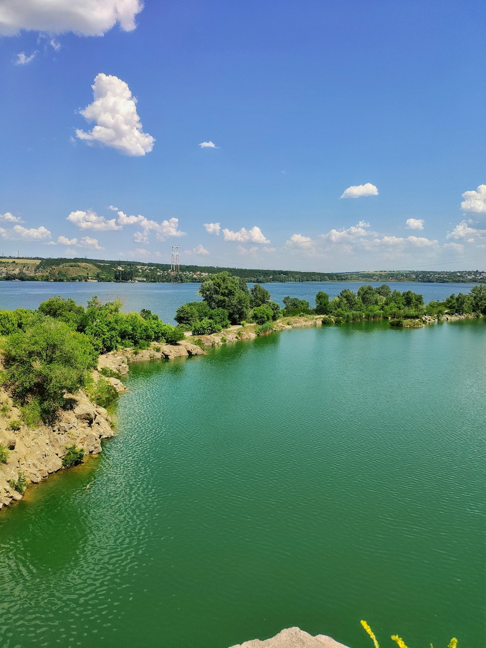 green trees beside blue lake under blue sky during daytime