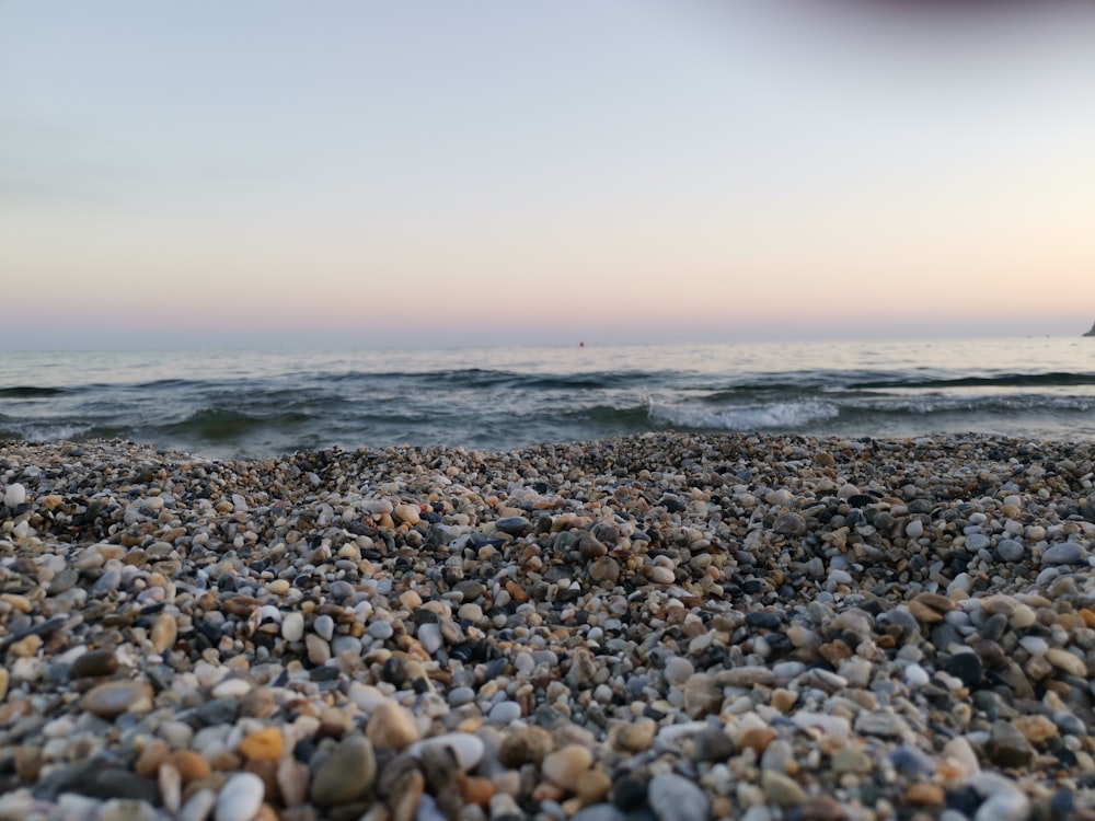 Piedras marrones y grises en la orilla del mar durante el día