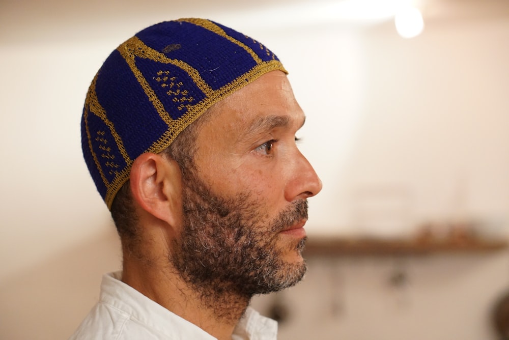 a man with a beard wearing a blue and gold hat