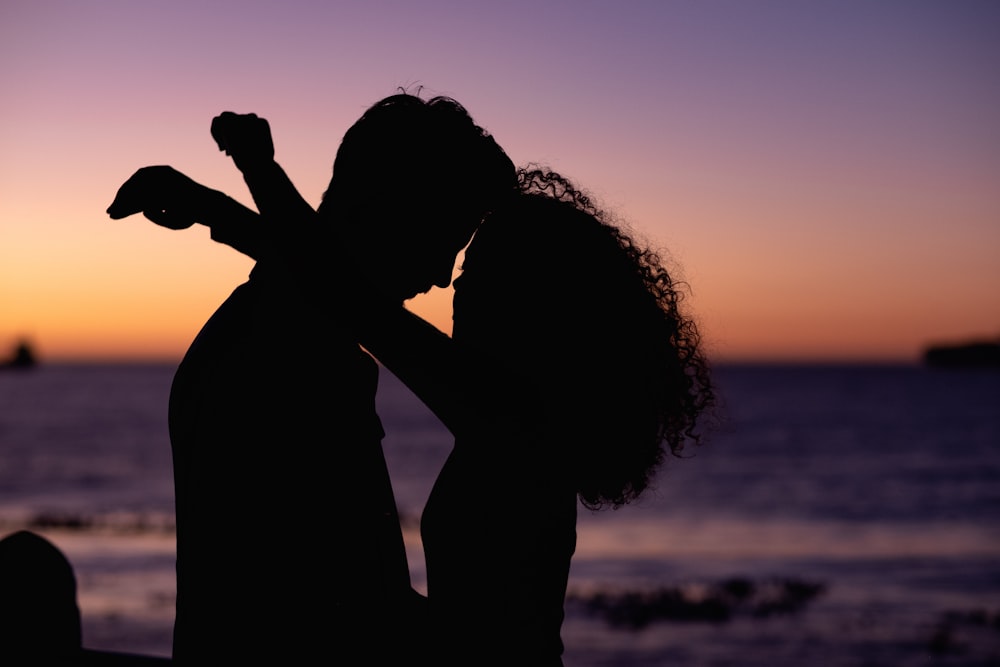 silhouette of man and woman kissing during sunset