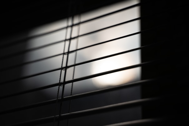 Close-up of sleek white blinds partially open, highlighting smooth texture and clean lines.