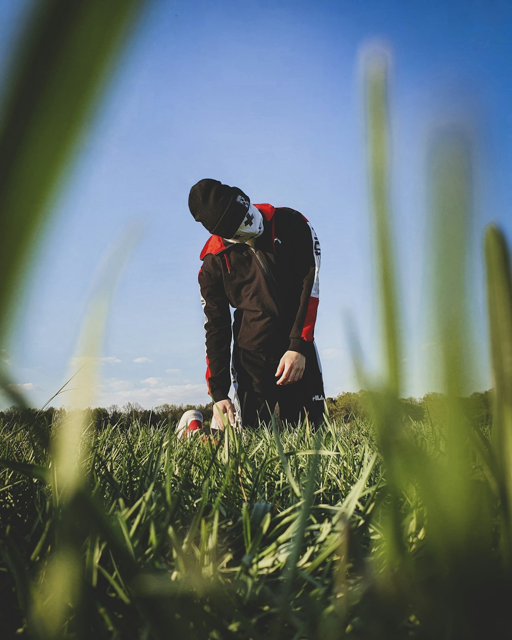 uomo in giacca nera e pantaloni neri in piedi sul campo di erba verde durante il giorno