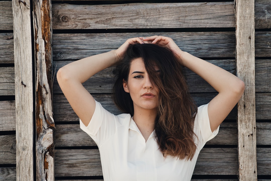 woman in white button up shirt standing on brown wooden plank