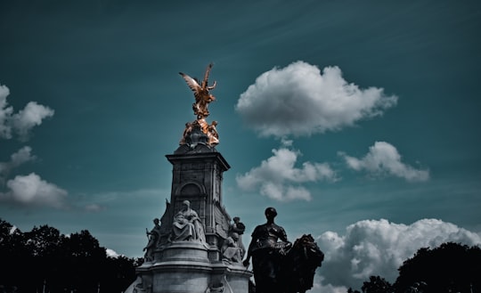 man in black coat statue under blue sky during daytime in Buckingham Palace Road United Kingdom
