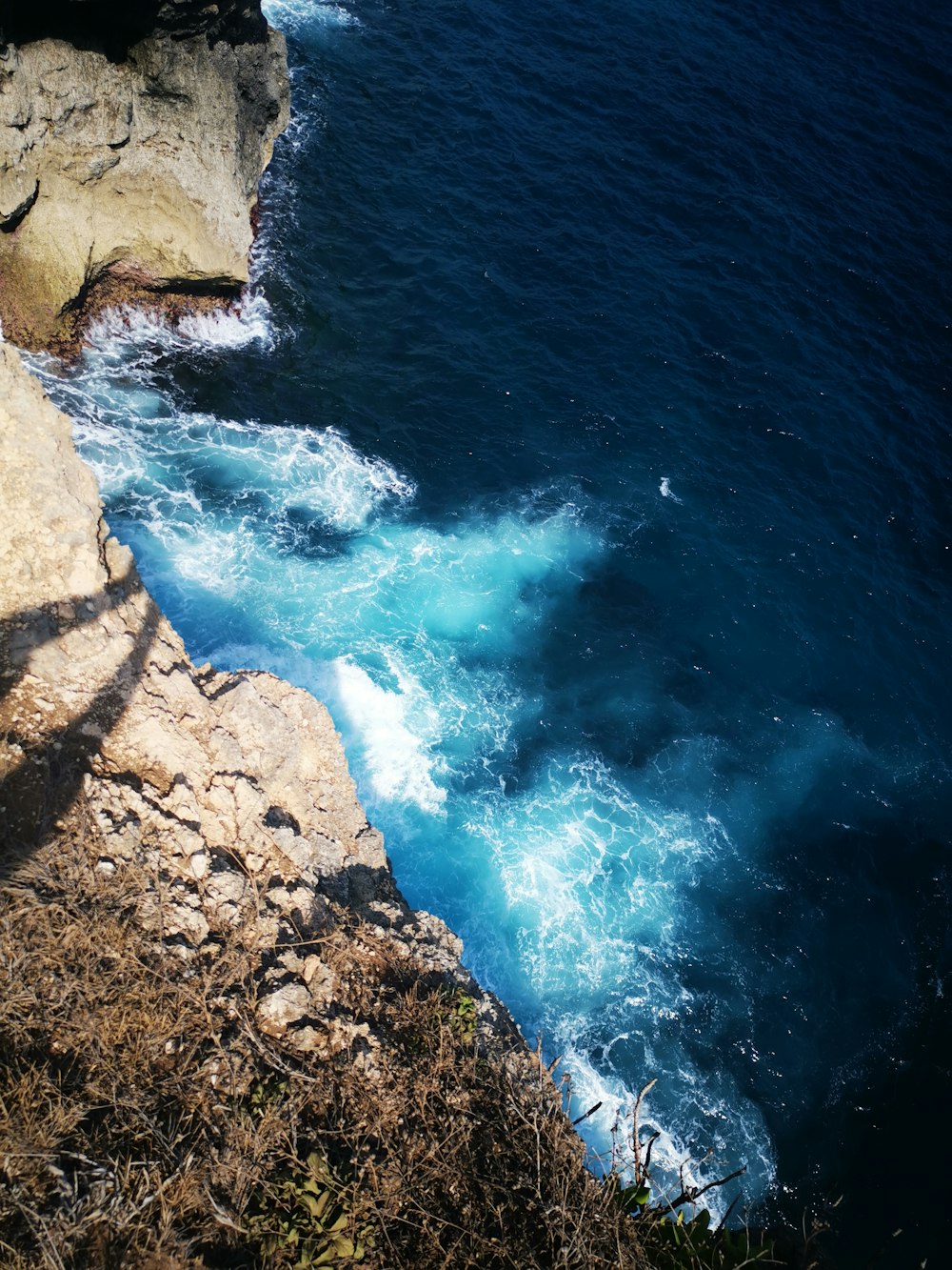brown rocky shore with blue water waves during daytime