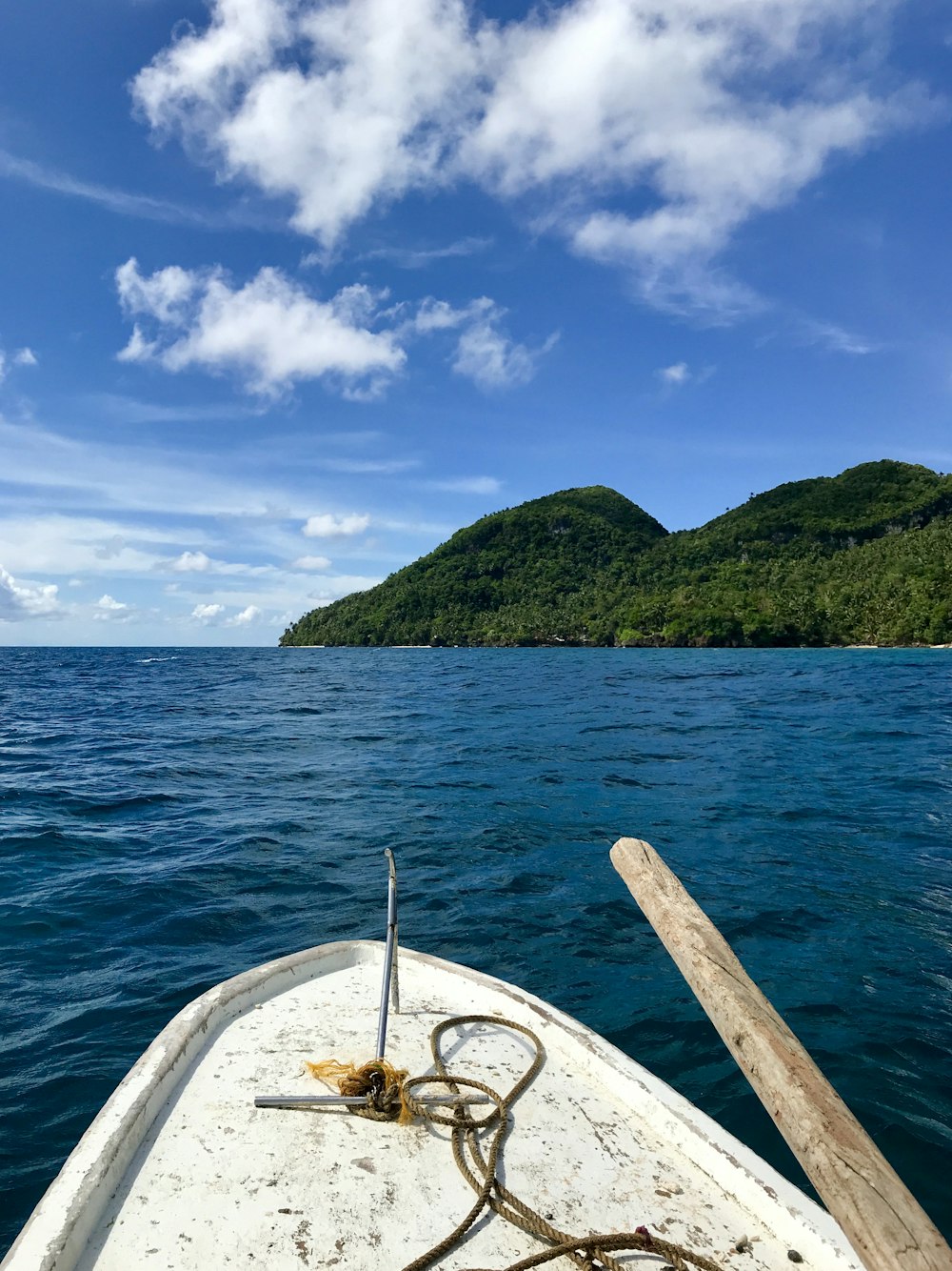 white boat on sea near green mountain under blue sky during daytime