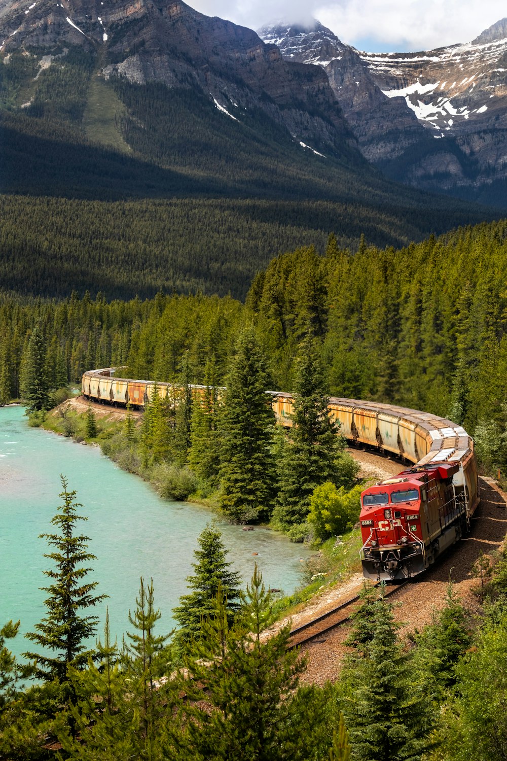 Train rouge et blanc sur rail près d’un plan d’eau pendant la journée