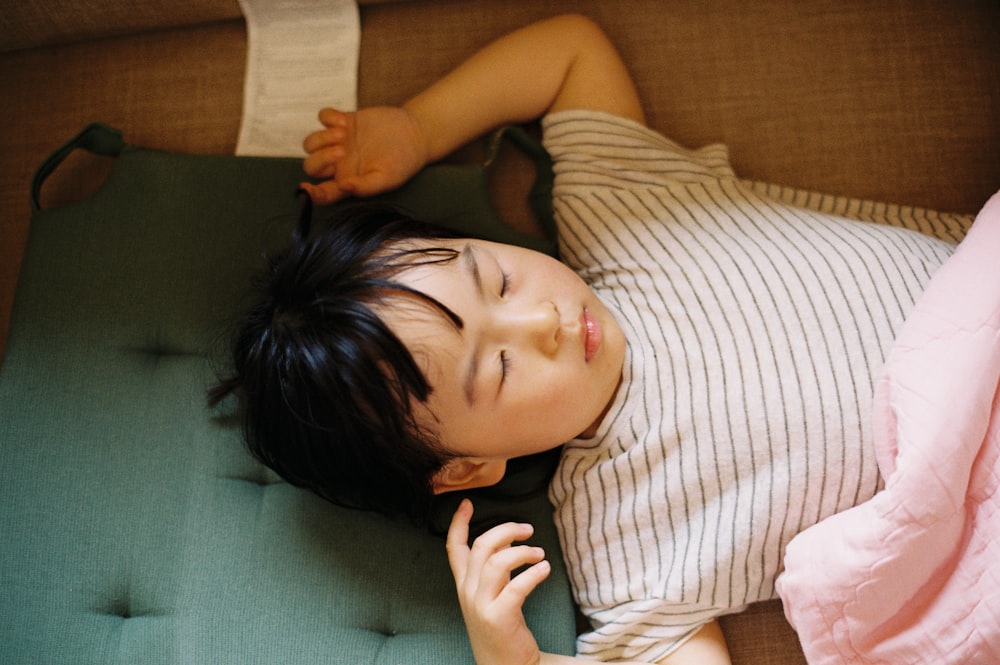 woman in white and brown stripe shirt lying on green bed