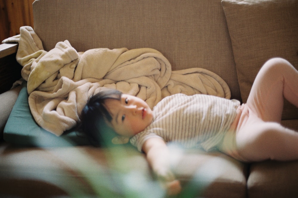 baby in white long sleeve shirt lying on bed