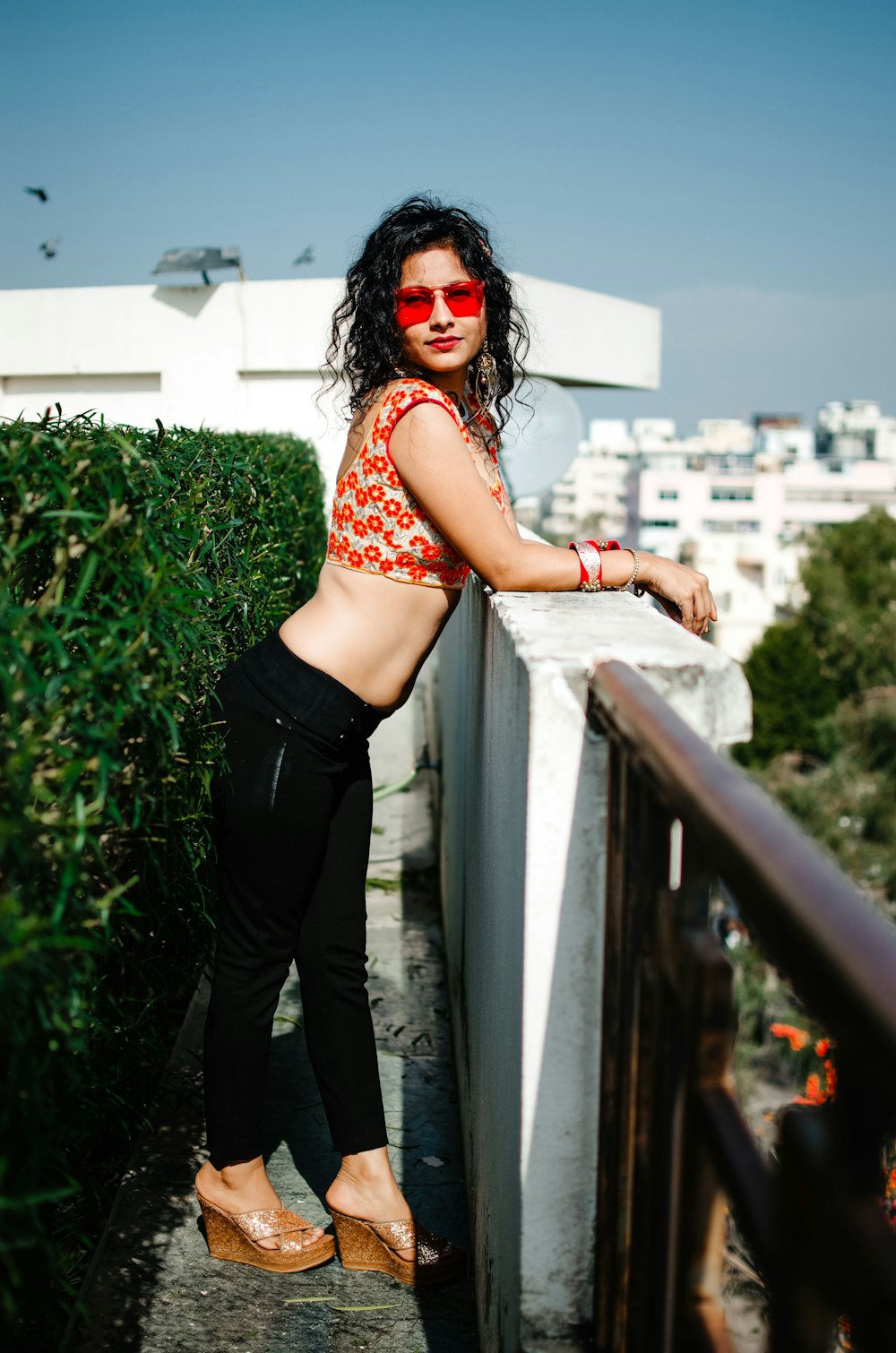 woman in red and white polka dot crop top and black pants wearing black sunglasses
