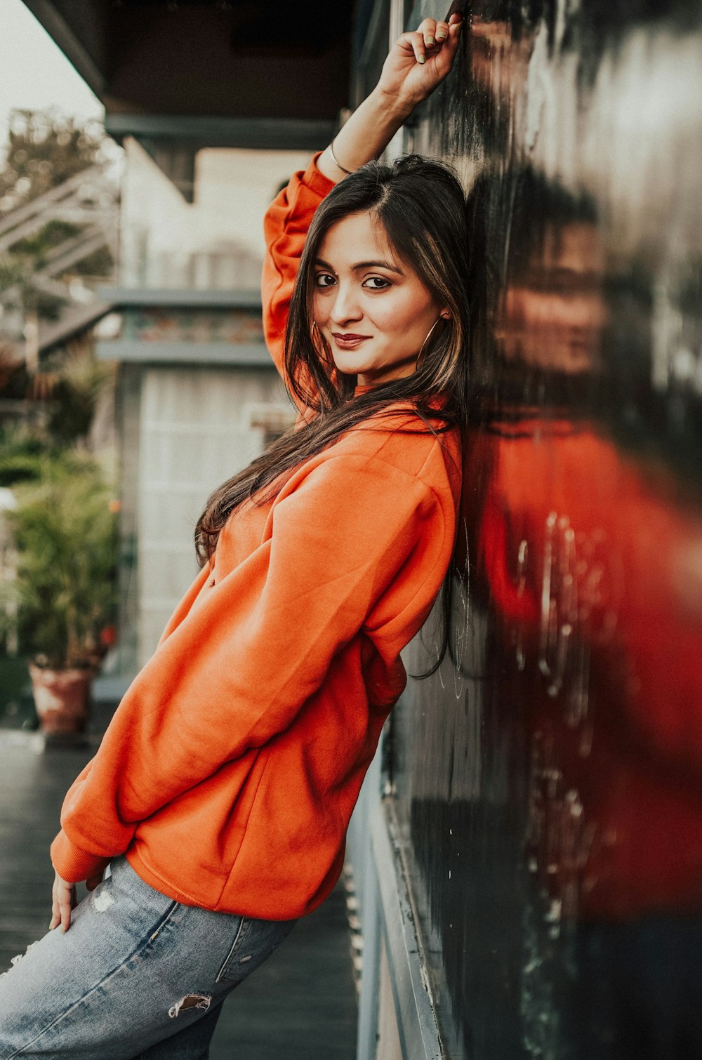woman in orange hoodie standing near glass wall