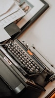 An artistic shot of a typewriter surrounded by scattered papers.