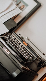 A vintage typewriter on a wooden desk with scattered old book pages around.