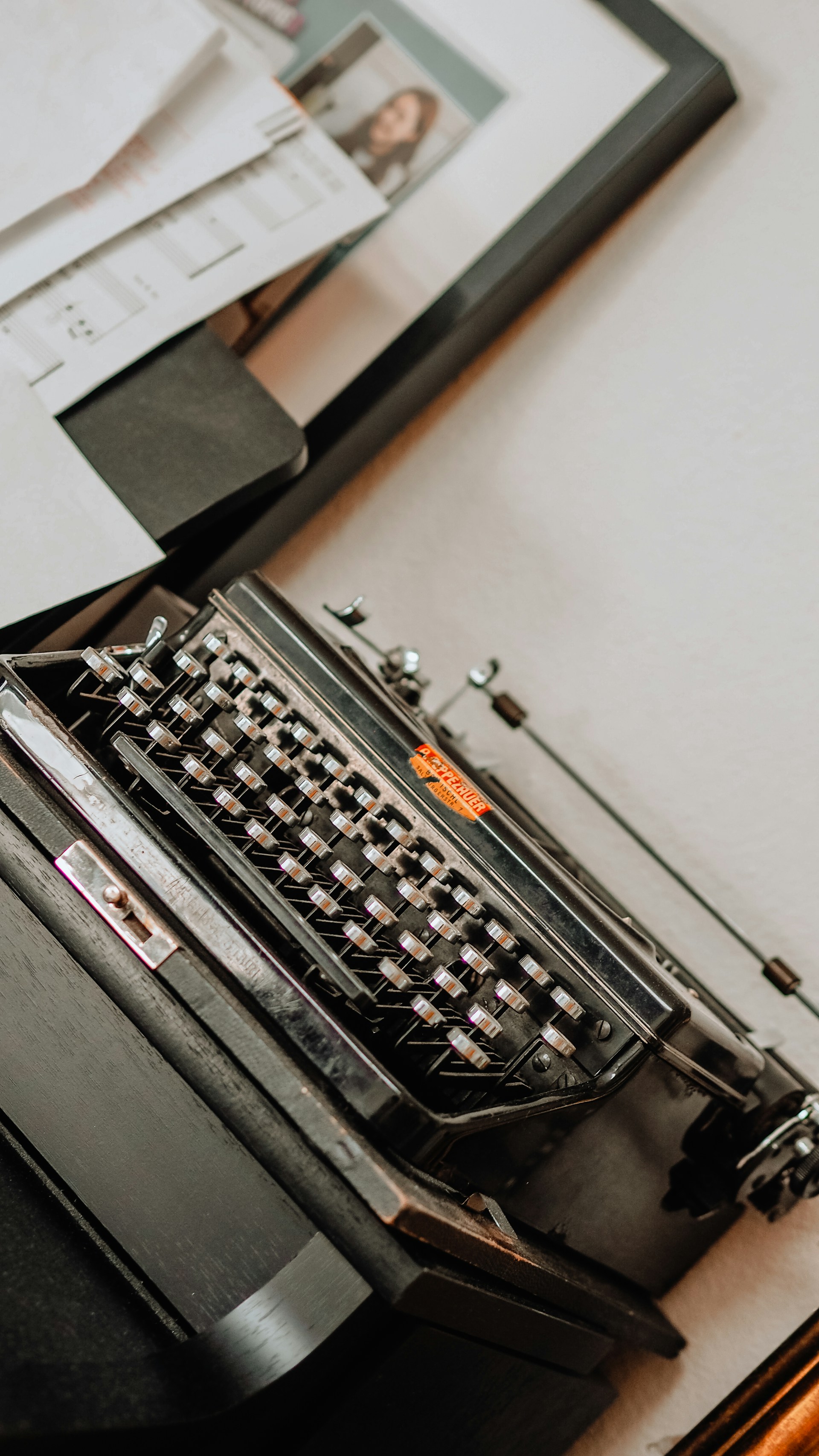 A close-up of a vintage typewriter surrounded by historical newspaper clippings and photographs.