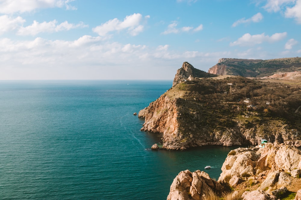 brown rock formation on sea under blue sky during daytime