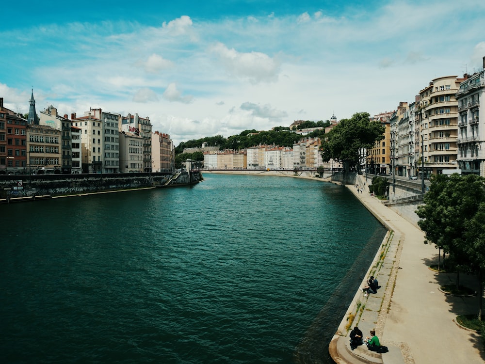 people walking on sidewalk near body of water during daytime