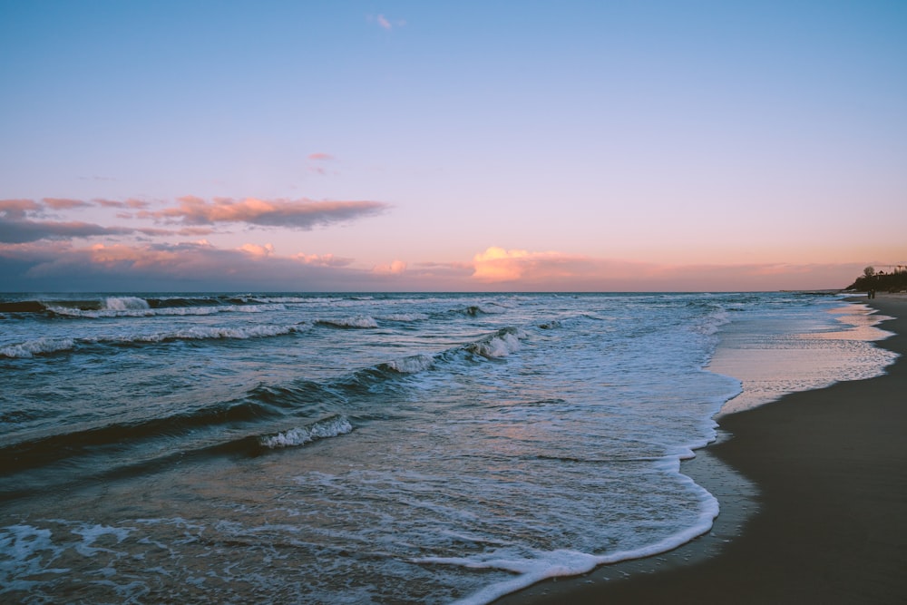 ocean waves crashing on shore during sunset