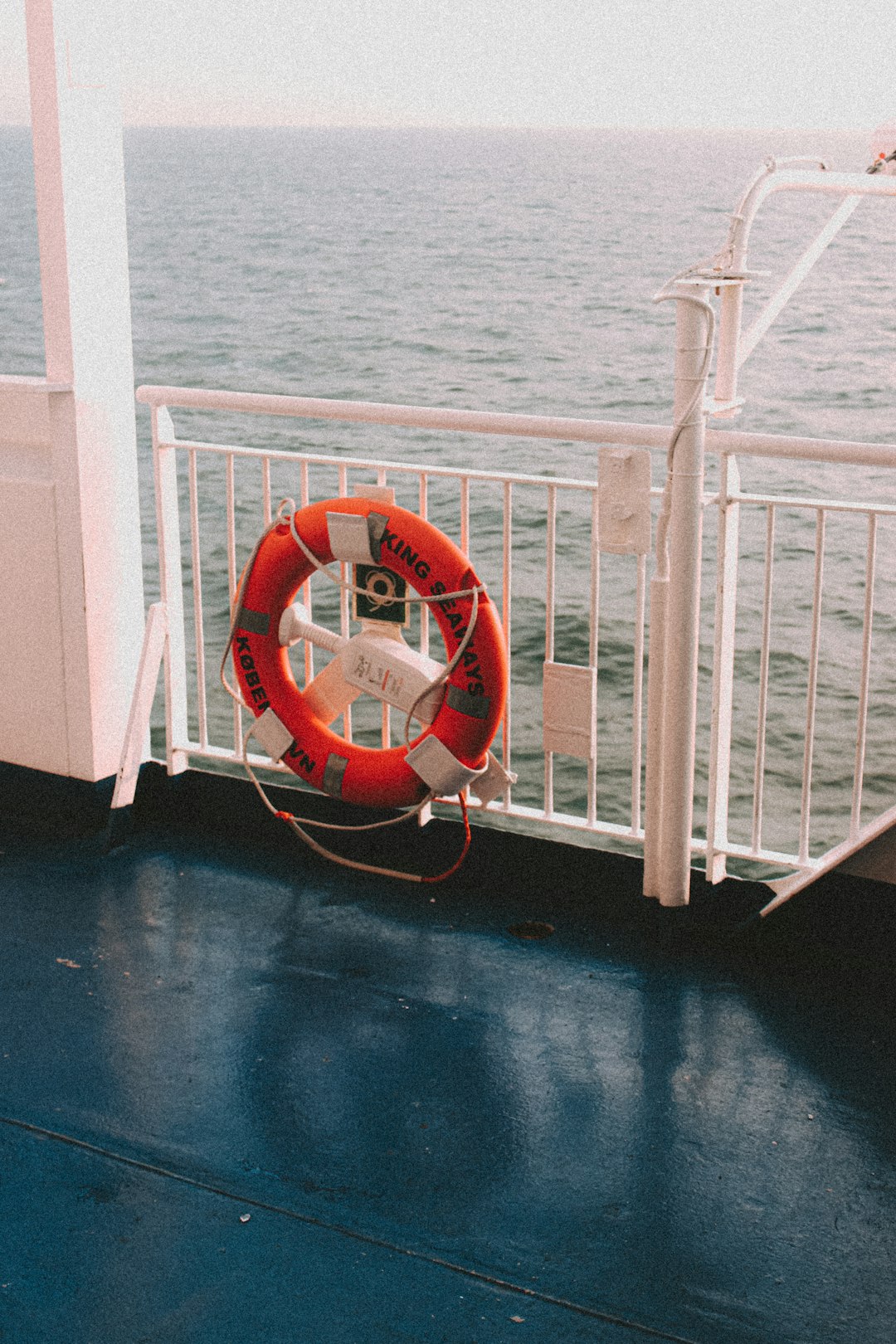 red and white life buoy on white wooden railings