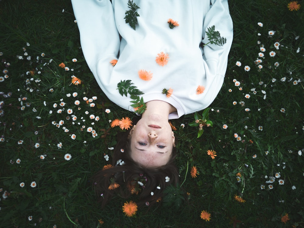 woman in white long sleeve shirt lying on white flower field