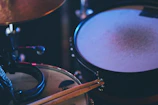 An intimate shot of a rehearsal space with drumsticks resting on a snare drum, ambient and minimal.