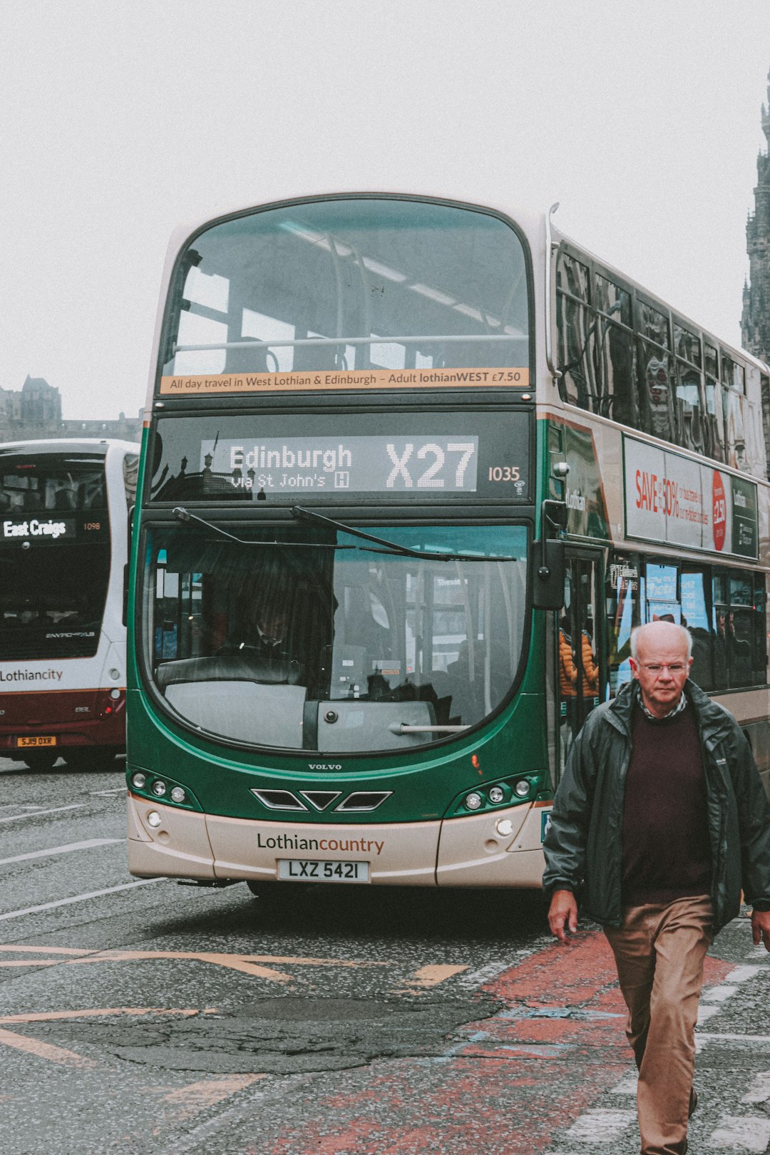 man in black jacket standing beside green and white bus during daytime