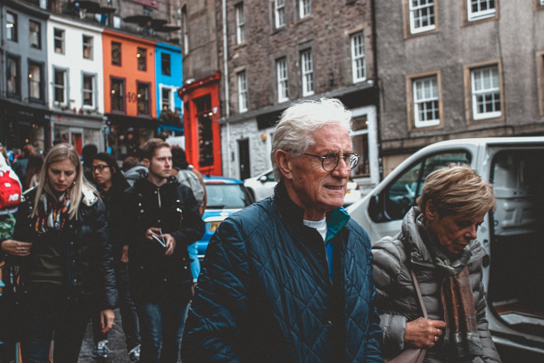 man in blue jacket standing near people walking on street during daytime