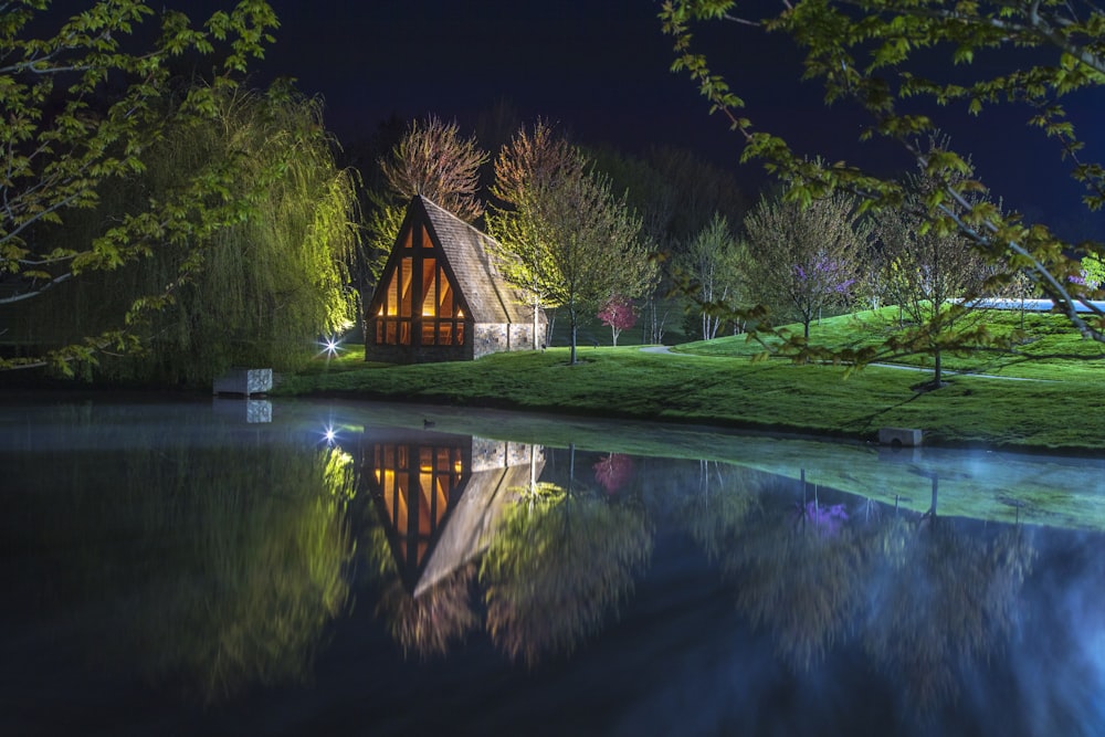 brown wooden house near lake and green trees