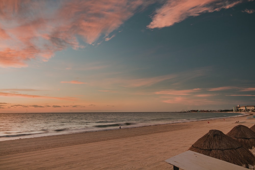 muelle de madera marrón en la playa durante la puesta del sol