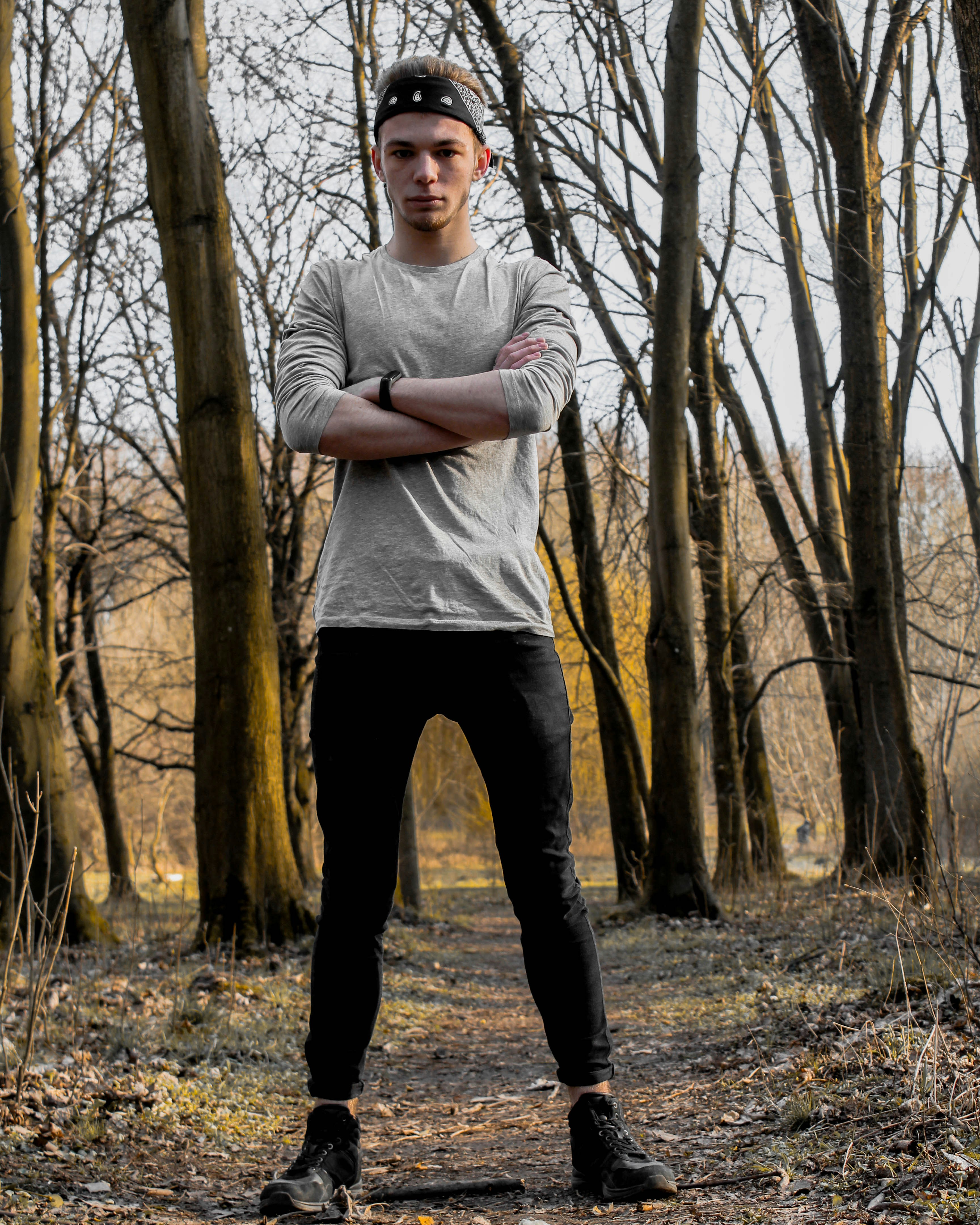 man in white long sleeve shirt and black pants standing on brown dried leaves during daytime